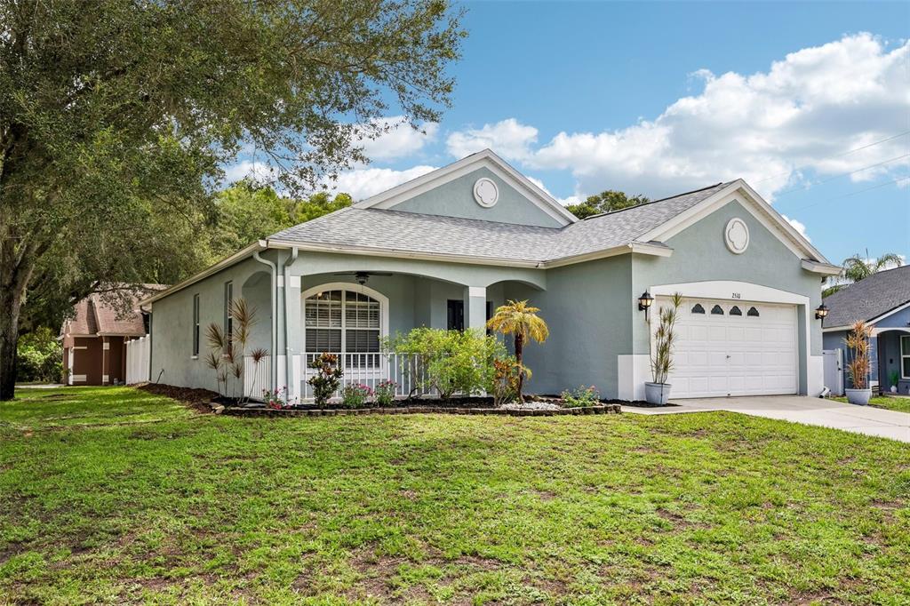 A light green single-story house with a two-car garage and a covered front porch — 2510 BUTTERFLY LANDING DRIVE, LAND O LAKES, FL