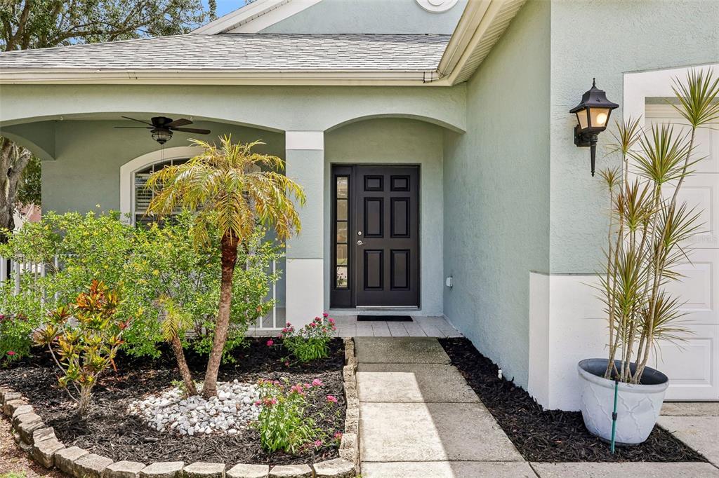 A front entryway features a dark door with glass panels, a walkway, and landscaped garden beds — 2510 BUTTERFLY LANDING DRIVE, LAND O LAKES, FL