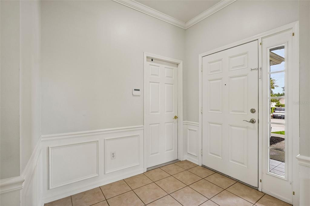 An entryway features tiled flooring, white wainscoting, a front door with a sidelight, and a closet — 2510 BUTTERFLY LANDING DRIVE, LAND O LAKES, FL