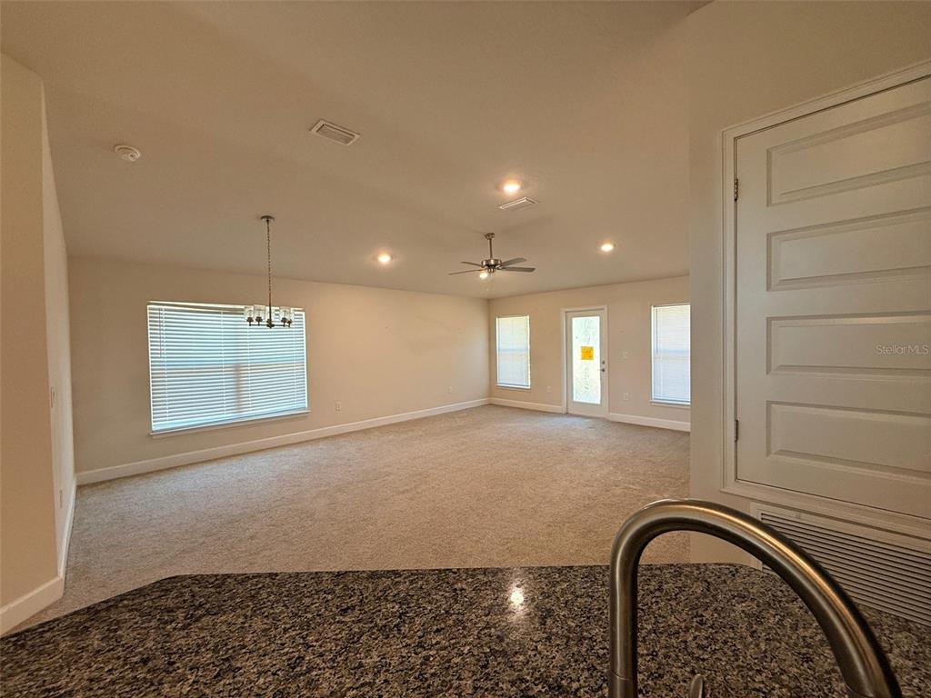 An open-concept living area features beige carpeting, recessed lighting, a ceiling fan, and a window — 910 HUDSON VALLEY DRIVE, KISSIMMEE, FL
