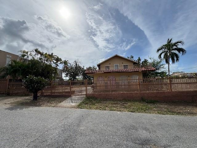 A two-story house with a fenced yard and palm trees under a cloudy sky — Calle 8 BO. PIEDRA AGUZA UNIT Casa 8, JUANA DIAZ, PR