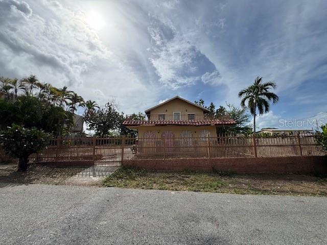 A two-story house with a fenced yard and a balcony under a cloudy sky — Calle 8 BO. PIEDRA AGUZA UNIT Casa 8, JUANA DIAZ, PR