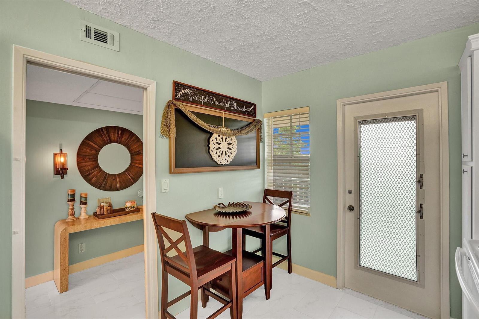 A small dining area with a wooden table, two chairs, and light green walls — 2940 N Course Drive # 511, Pompano Beach FL 33069, POMPANO BEACH, FL