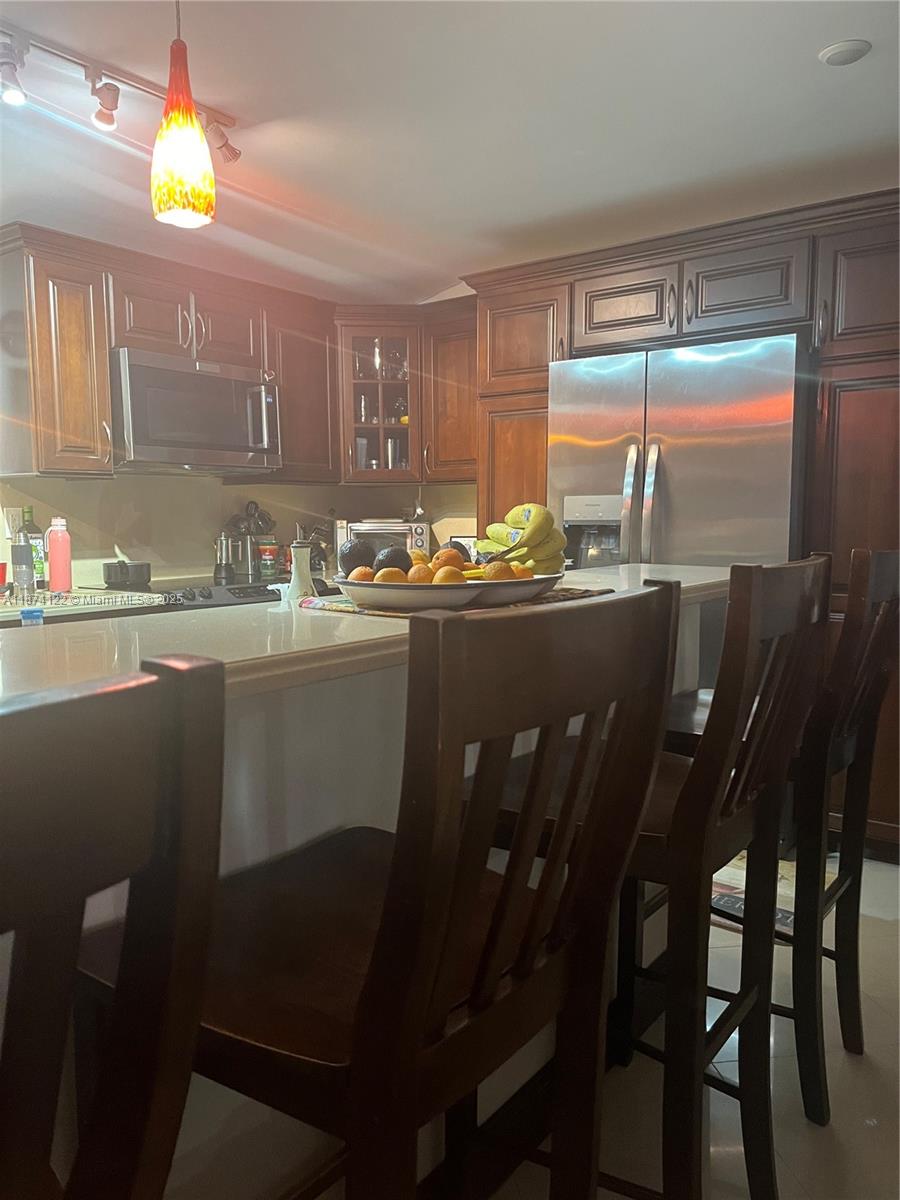 A kitchen features dark wood cabinetry, stainless steel appliances, and a breakfast bar with stools — 7521 SW 57th Ter, Miami FL 33143, MIAMI, FL