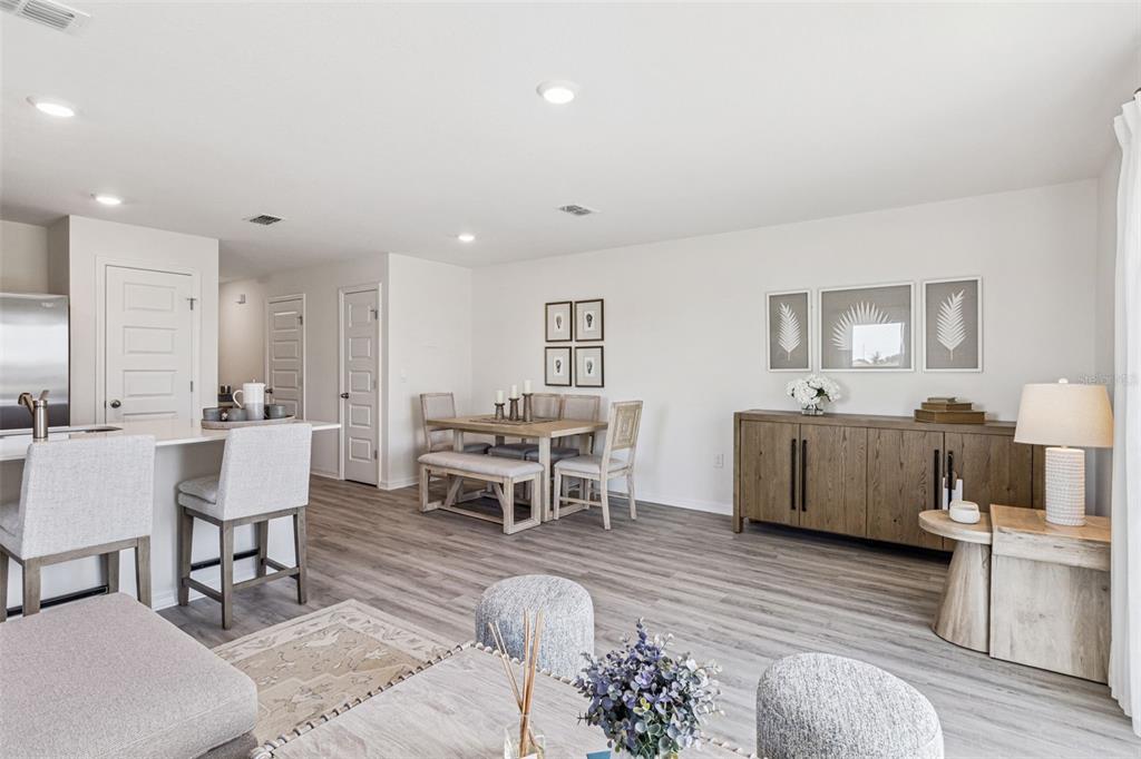 An open-concept dining area features a wooden table, chairs, and a sideboard on wood flooring — 4715 TONY STREET, LAKE WALES, FL