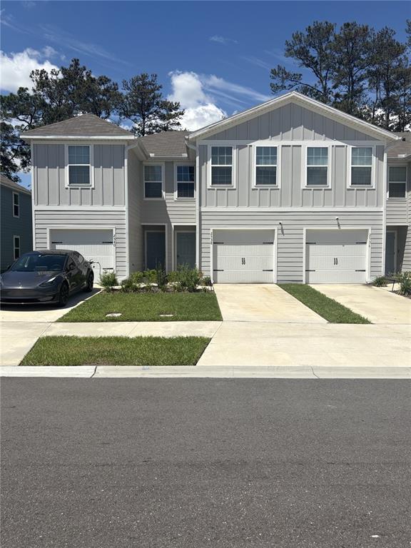 A multi-unit residential building features light gray siding, white garage doors, and a paved driveway — 2538 SADLER TRACE WAY, JACKSONVILLE, FL