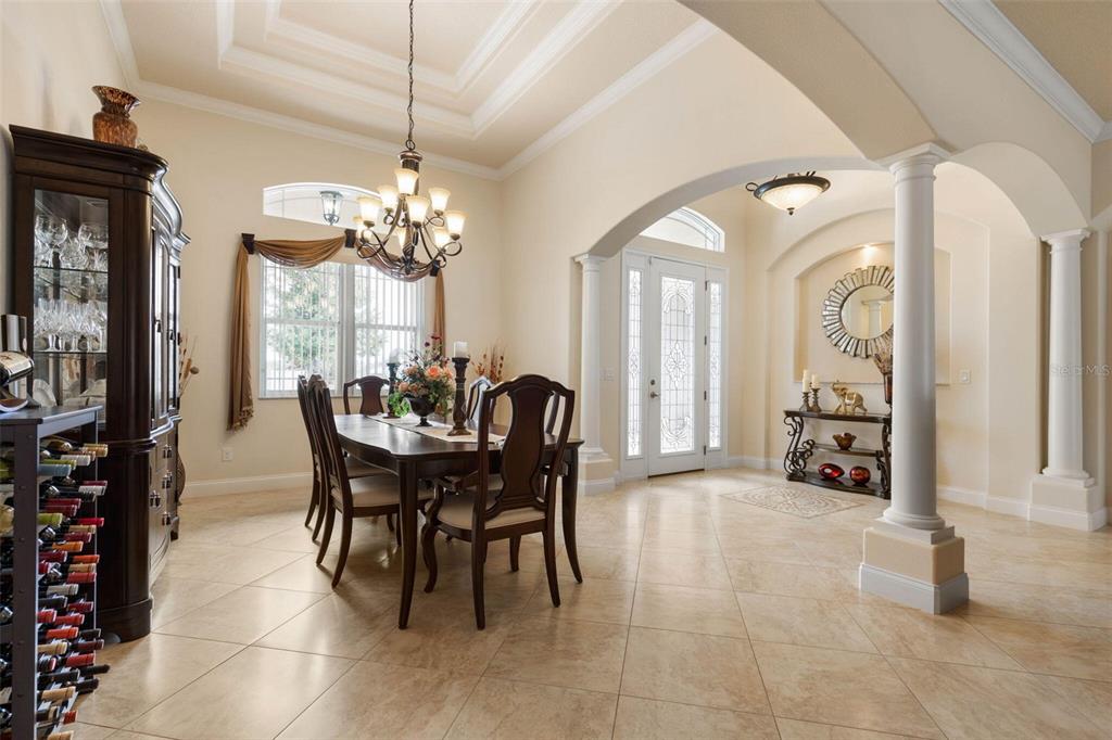 A dining room with tile floors, a dark wood table, and an arched entryway — 60 FENIMORE LANE, PALM COAST, FL