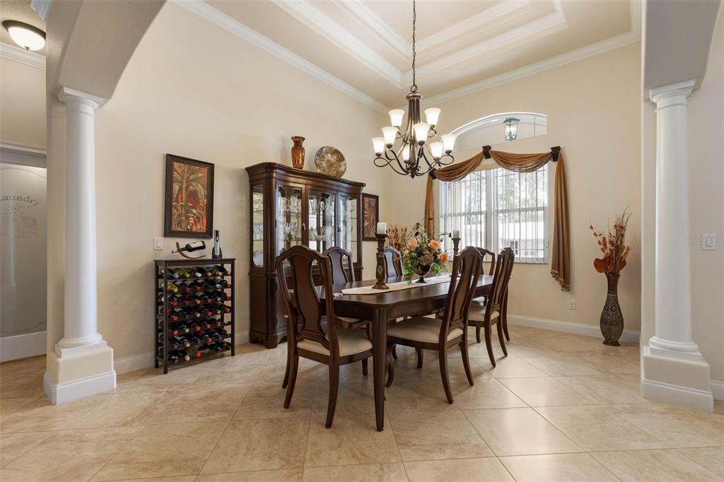A formal dining room features a dark wood table, matching chairs, a china cabinet, and tile flooring — 60 FENIMORE LANE, PALM COAST, FL