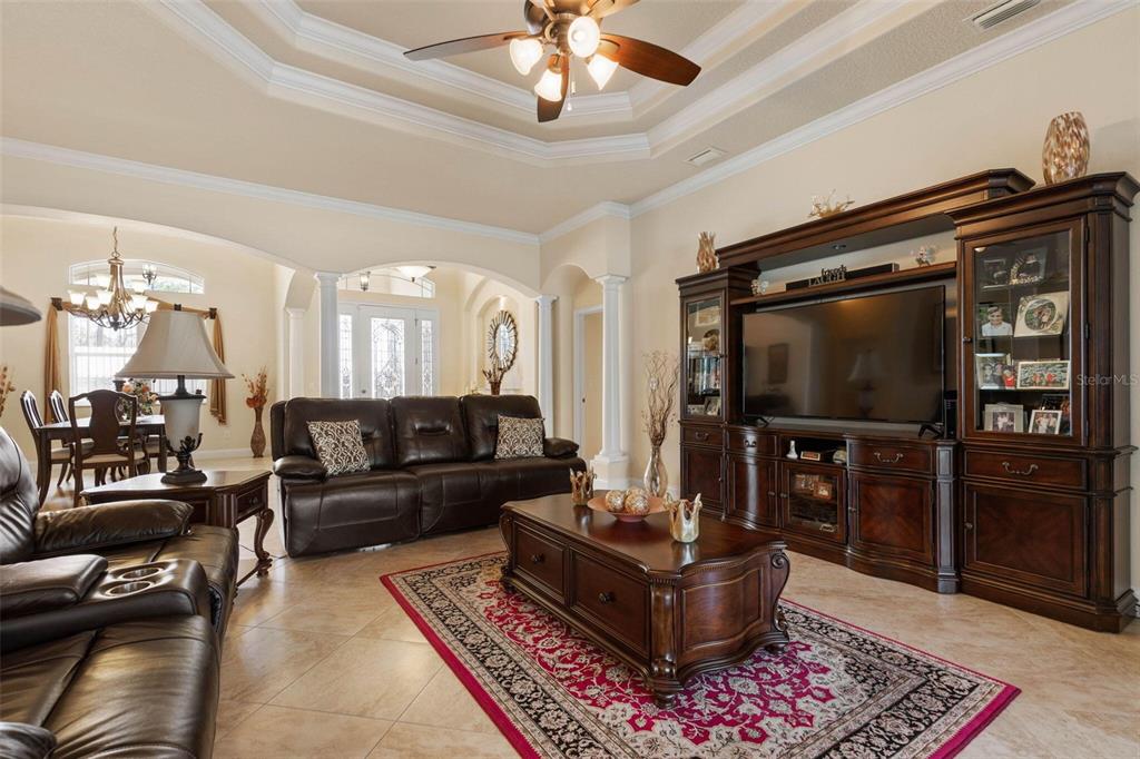 A living room features a dark leather sofa, a wooden entertainment center, and tile flooring — 60 FENIMORE LANE, PALM COAST, FL