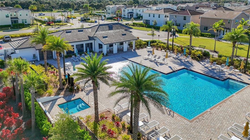 An aerial view of a community swimming pool, hot tub, and clubhouse with palm trees — 5414 LATCHES LANE UNIT 4B-Haven, LAKEWOOD RANCH, FL