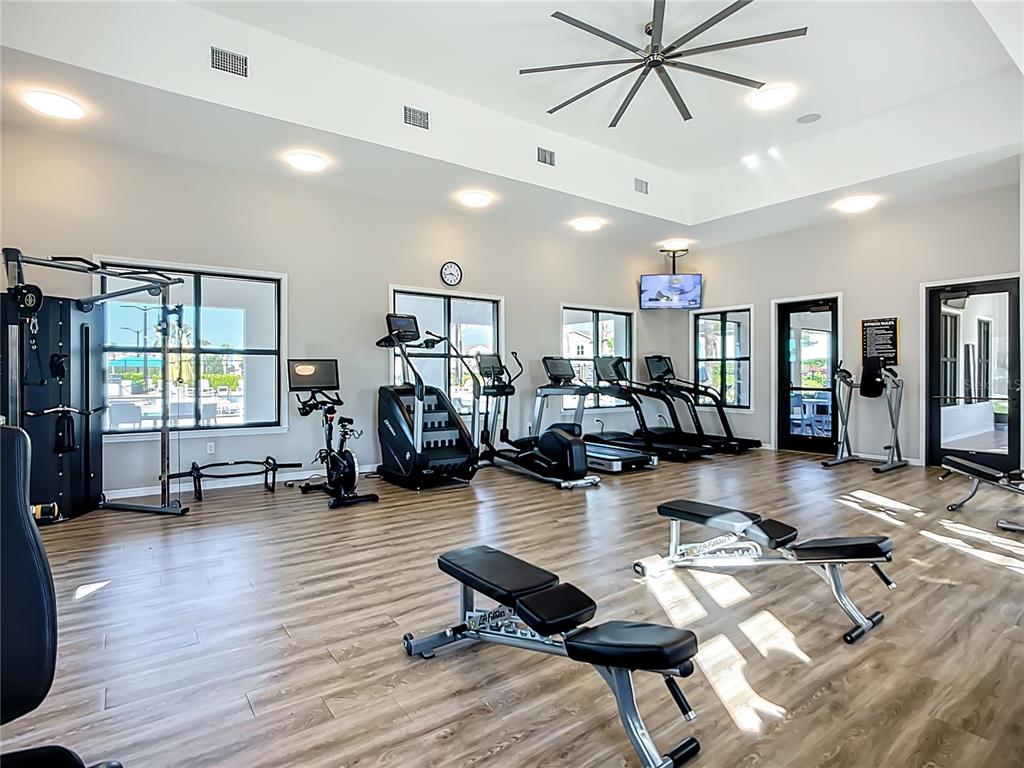 A bright fitness center features wood-look flooring, various exercise machines, and a large ceiling fan — 5414 LATCHES LANE UNIT 4B-Haven, LAKEWOOD RANCH, FL