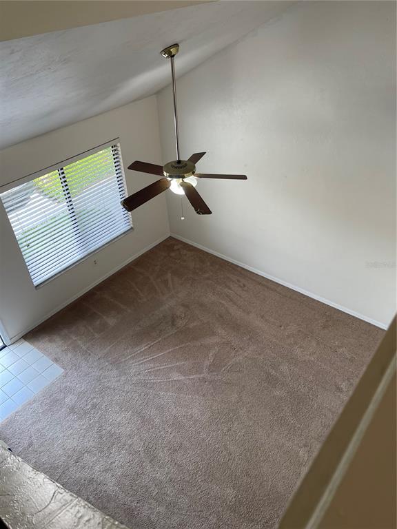 A high-angle view of a carpeted living room with a vaulted ceiling and ceiling fan — 3504 NW 37TH AVENUE, GAINESVILLE, FL
