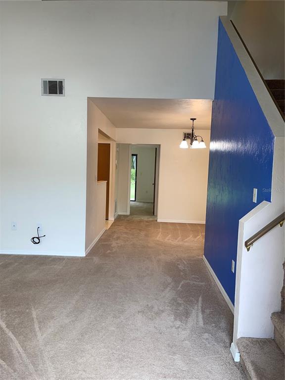 An interior view shows a carpeted living area with a blue accent wall and staircase — 3504 NW 37TH AVENUE, GAINESVILLE, FL