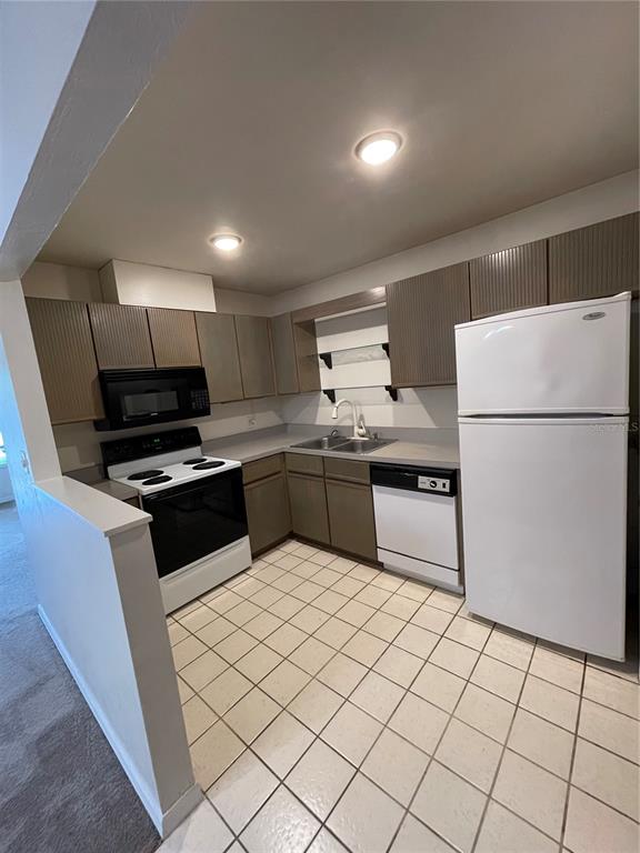 A kitchen features brown cabinets, white appliances, a tiled floor, and a peninsula counter — 3504 NW 37TH AVENUE, GAINESVILLE, FL