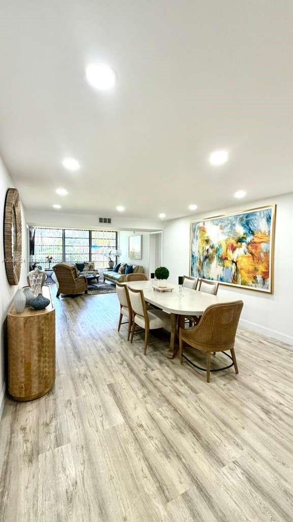 A dining area with a light-colored table and chairs sits in an open-concept living space — 1721 Whitehall Dr # 101, Davie FL 33324, DAVIE, FL