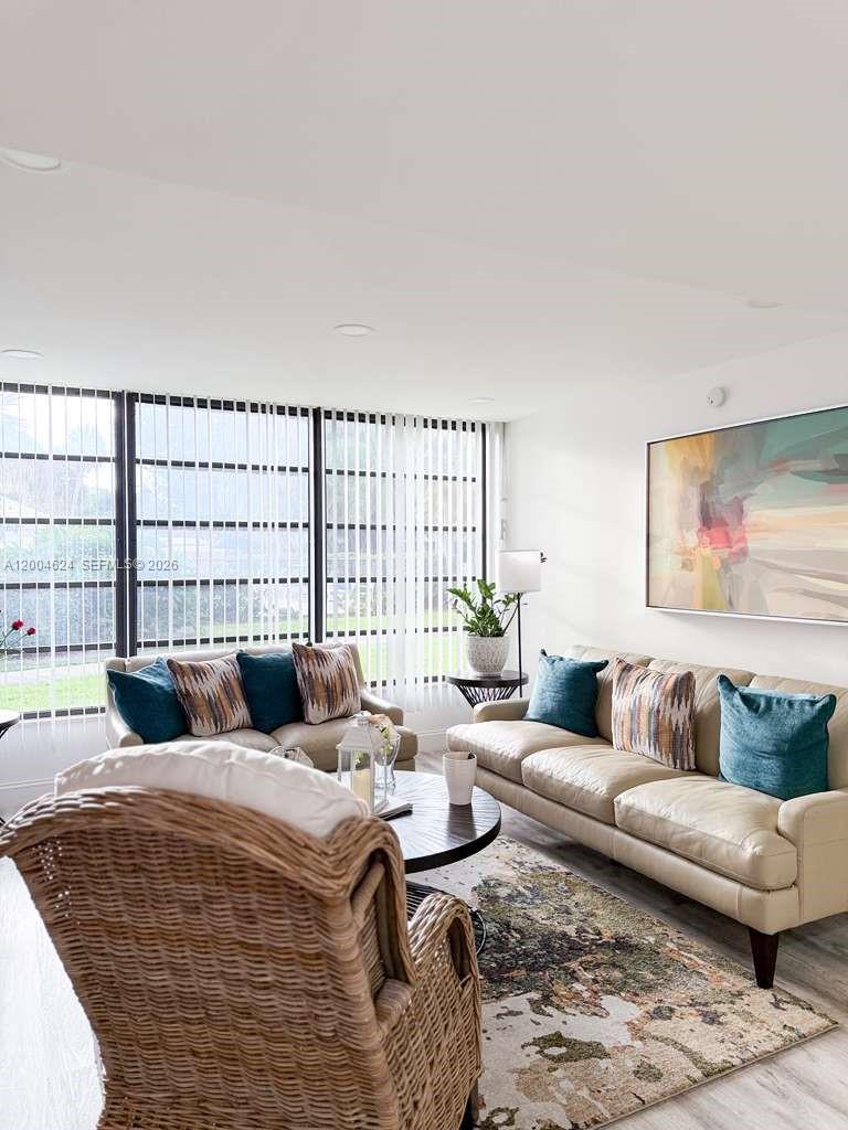 A living room features two beige sofas, a wicker armchair, and large floor-to-ceiling windows — 1721 Whitehall Dr # 101, Davie FL 33324, DAVIE, FL