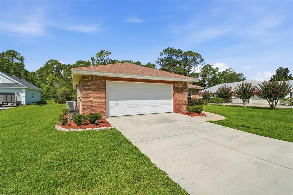 A brick-front house with a two-car garage and a concrete driveway on a grassy lot — 687 WINTERBERRY TRAIL, DELAND, FL