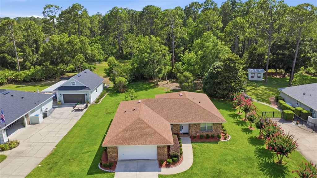 An aerial view shows a single-story brick house with a brown roof and attached garage — 687 WINTERBERRY TRAIL, DELAND, FL