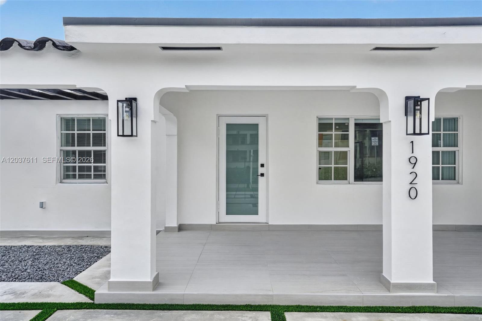 The exterior of a white house features a covered porch with tiled flooring and columns — 1920 SW 67th Ave, Miami FL 33147, MIAMI, FL