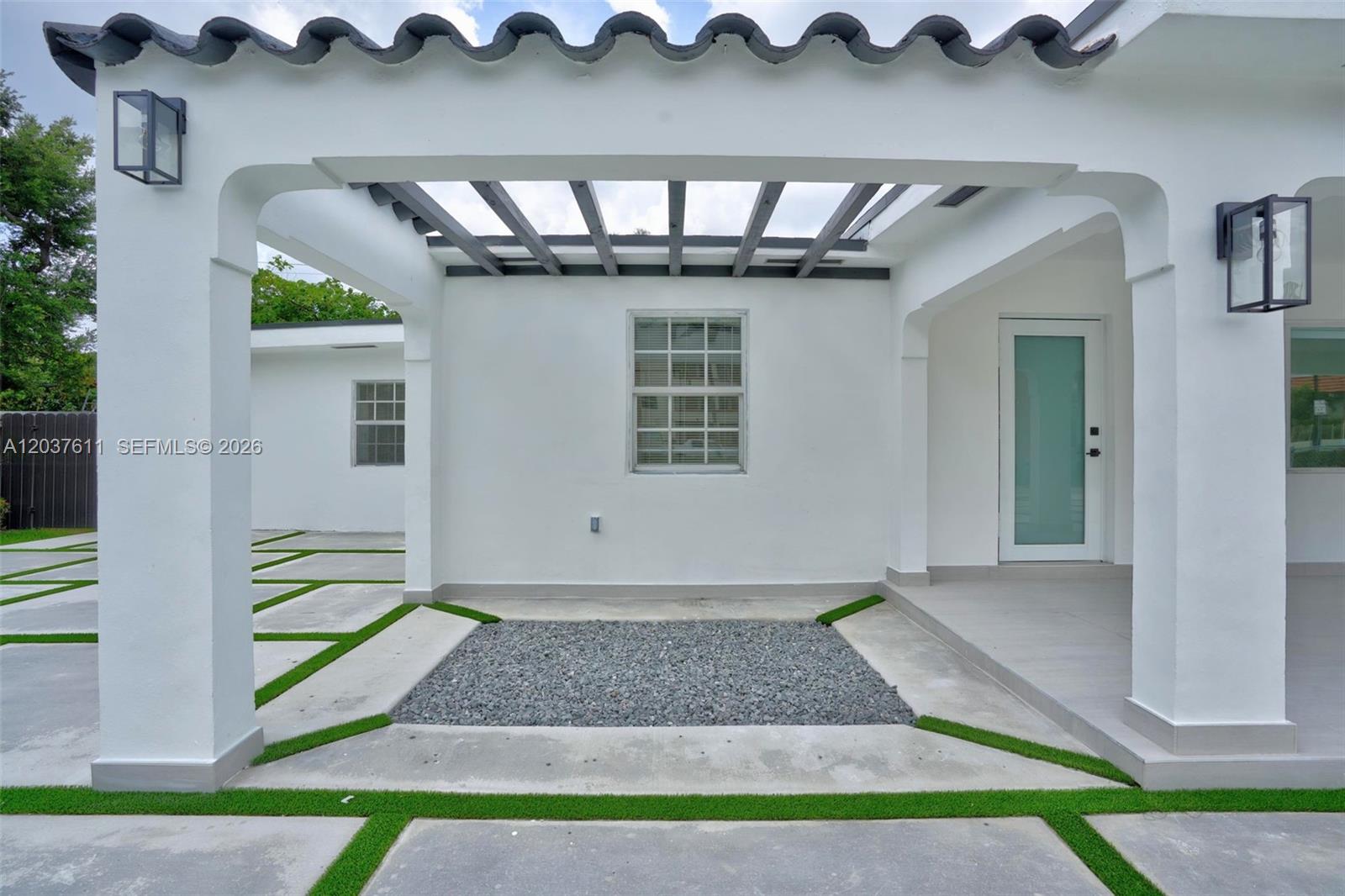 A white exterior wall features a central window, a pergola, and a gravel garden bed — 1920 SW 67th Ave, Miami FL 33147, MIAMI, FL