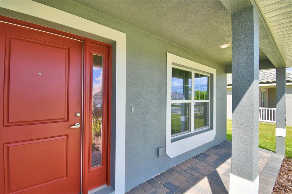 A light gray house exterior features a teal front door and a paver walkway — 4467 JULIANA LAKE DRIVE, AUBURNDALE, FL