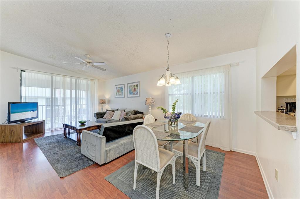 A living and dining area with wood-look flooring, a glass table, and a sofa — 4320 47TH AVENUE W UNIT 204, BRADENTON, FL