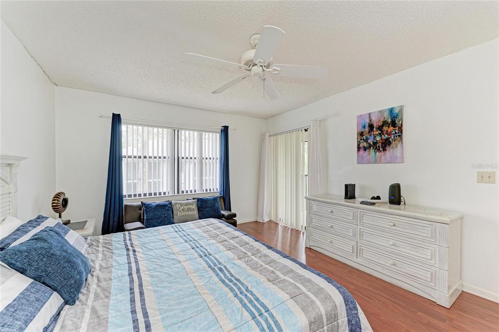 A bedroom features a bed with blue striped bedding, a white dresser, and a ceiling fan — 4320 47TH AVENUE W UNIT 204, BRADENTON, FL