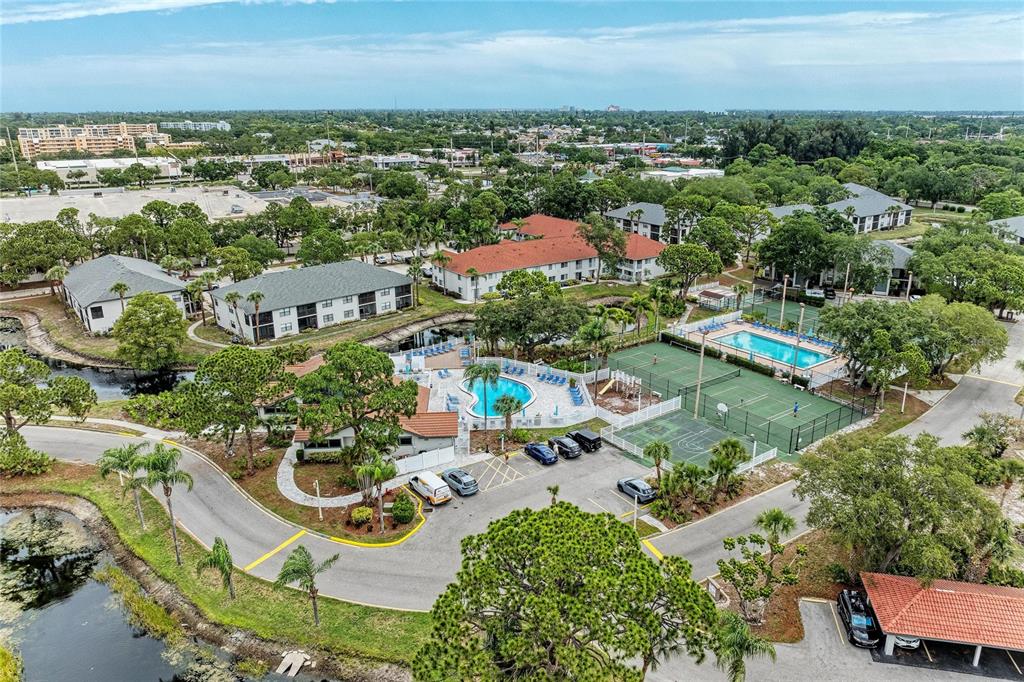 Aerial view of a residential complex featuring a swimming pool, tennis courts, and parking area — 4320 47TH AVENUE W UNIT 204, BRADENTON, FL