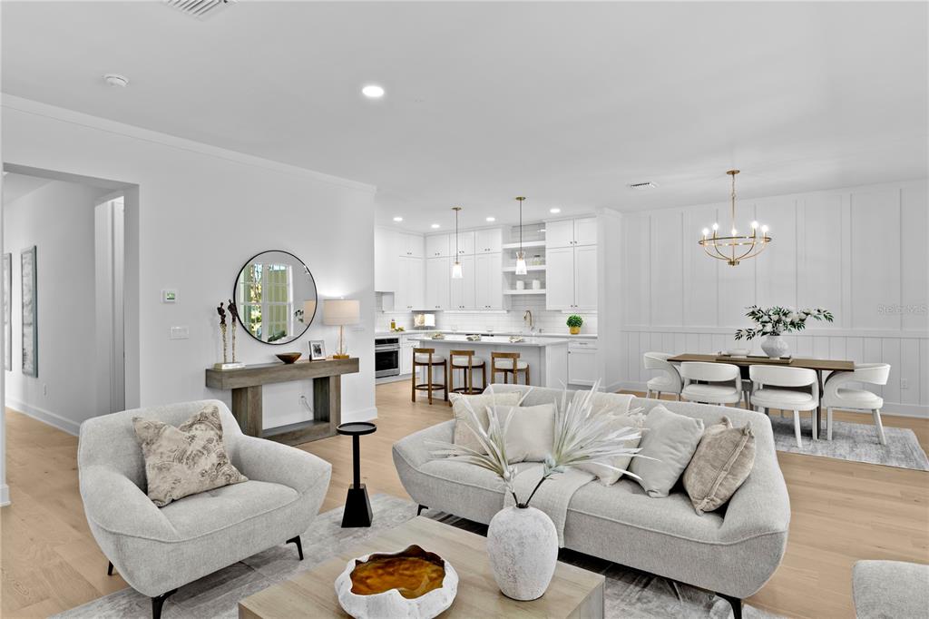 An open-concept living room and kitchen feature white cabinetry, light wood flooring, and modern furniture — 450 GILMAN PLACE N, ST PETERSBURG, FL