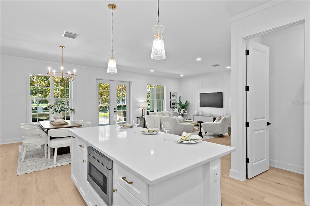 A white kitchen island with a built-in microwave overlooks an open-concept living and dining area — 450 GILMAN PLACE N, ST PETERSBURG, FL