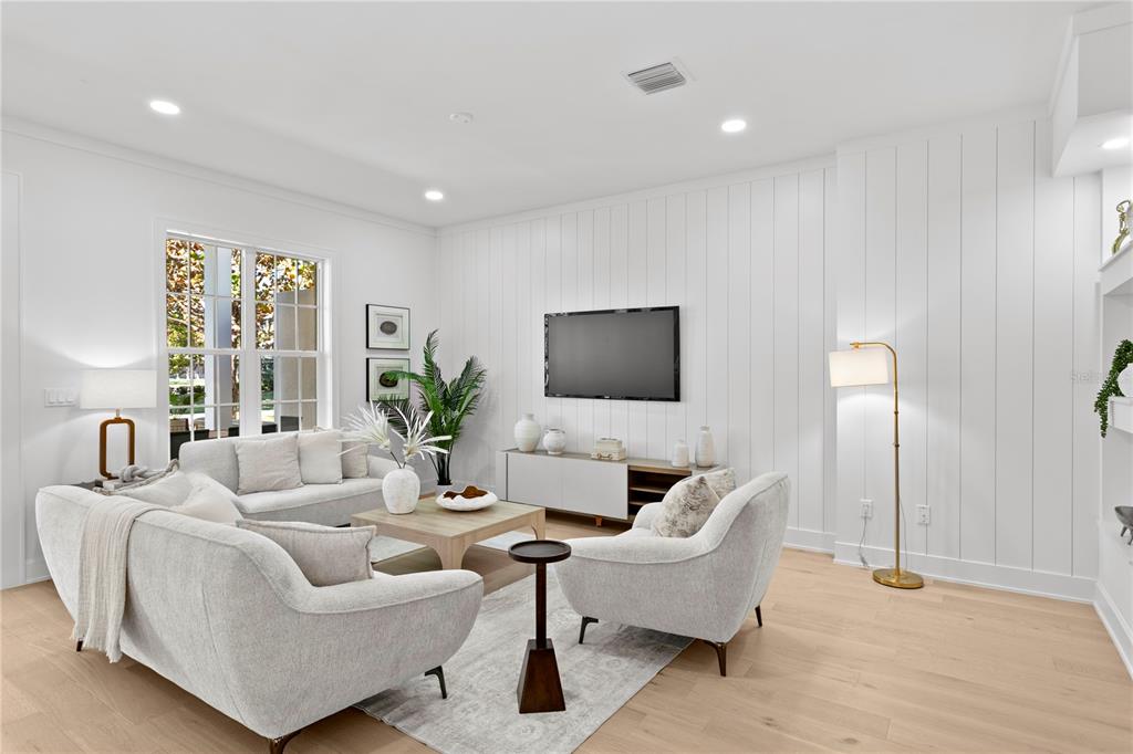 A bright living room features white vertical shiplap walls, light wood flooring, and modern furniture — 450 GILMAN PLACE N, ST PETERSBURG, FL