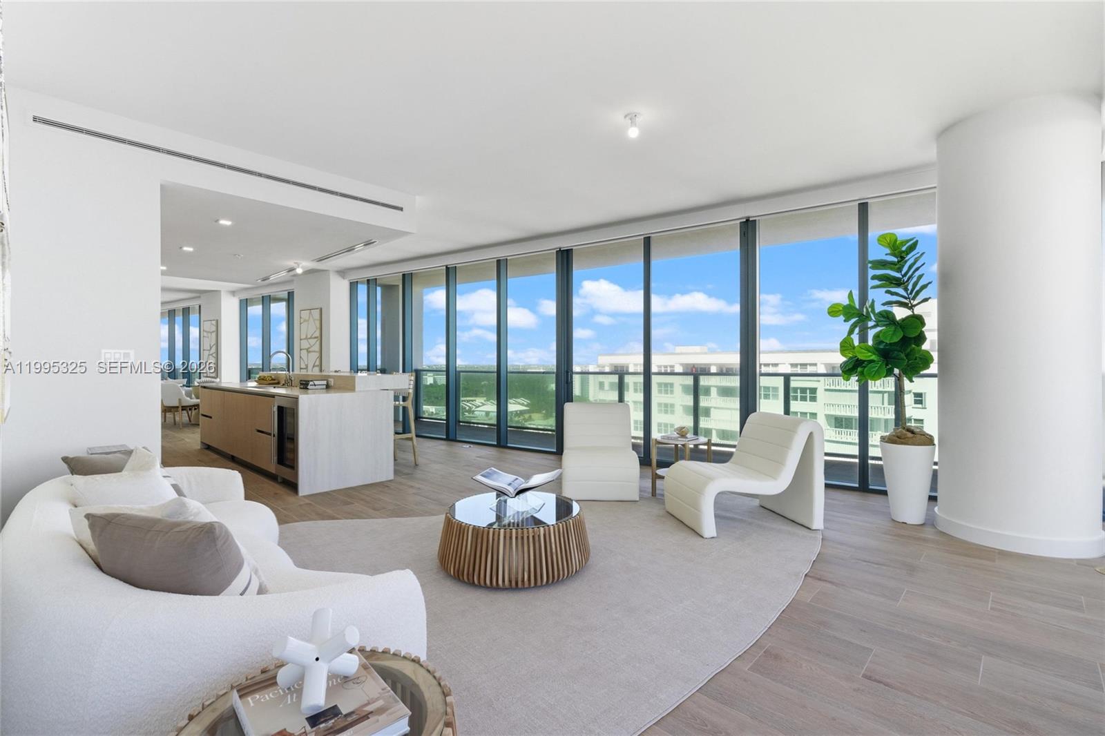 A modern living room features floor-to-ceiling windows, light wood flooring, and an open kitchen area — 900 N Ocean Blvd # 1506, Pompano Beach FL 33062, POMPANO BEACH, FL