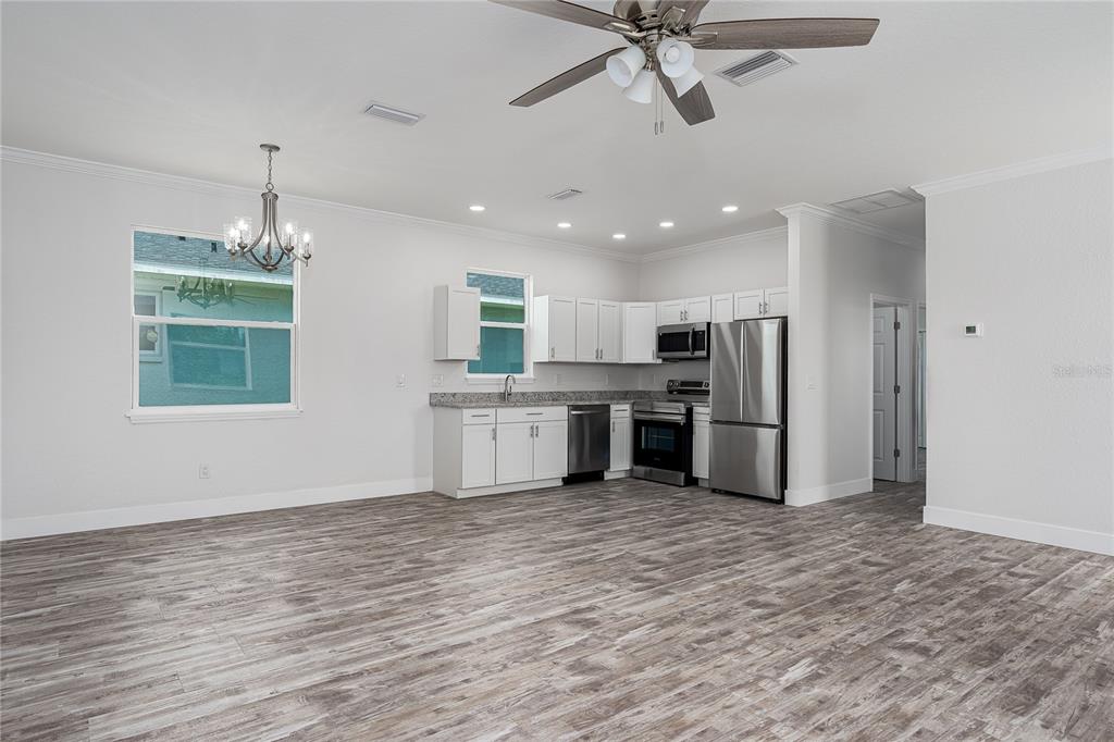A kitchen with white cabinets, stainless steel appliances, and wood-look flooring in an open room — 1515 2ND AVENUE W, PALMETTO, FL