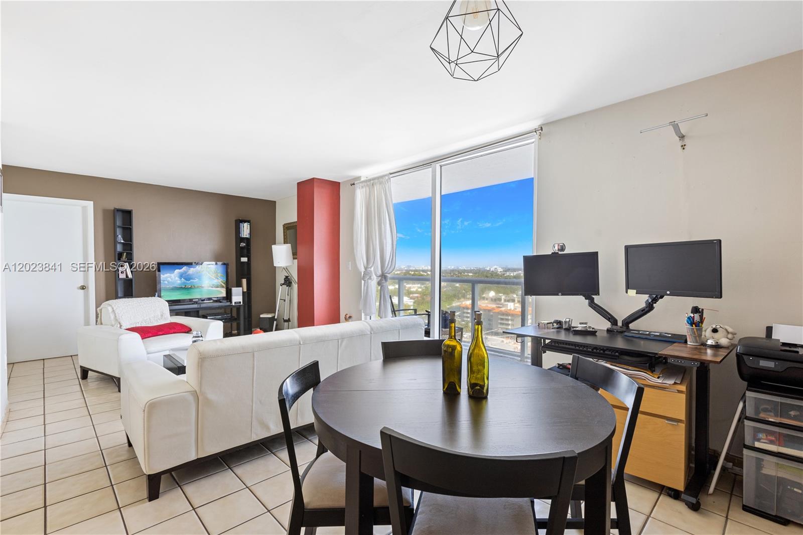 A living and dining area features tile floors, a white sofa, and a balcony view — 2457 Collins Ave # 1602, Miami Beach FL 33140, MIAMI BEACH, FL