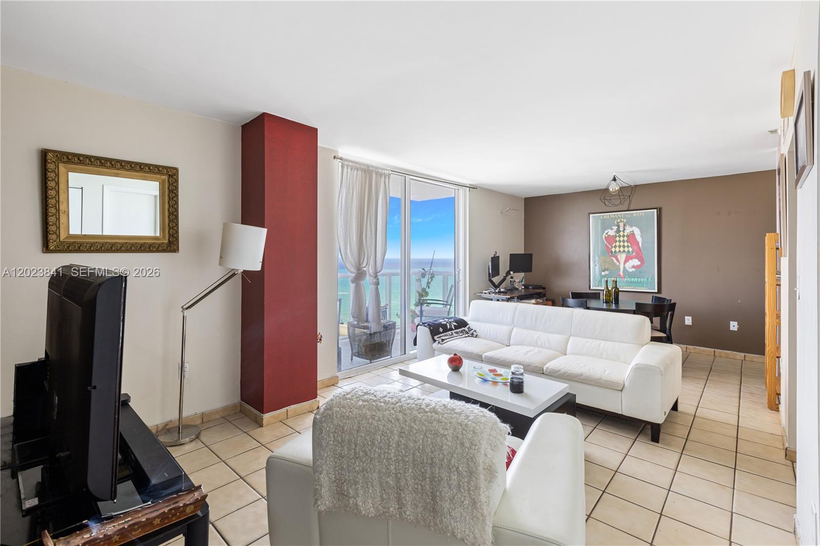 A living room with tile floors, a white sofa, and a balcony overlooking the ocean — 2457 Collins Ave # 1602, Miami Beach FL 33140, MIAMI BEACH, FL