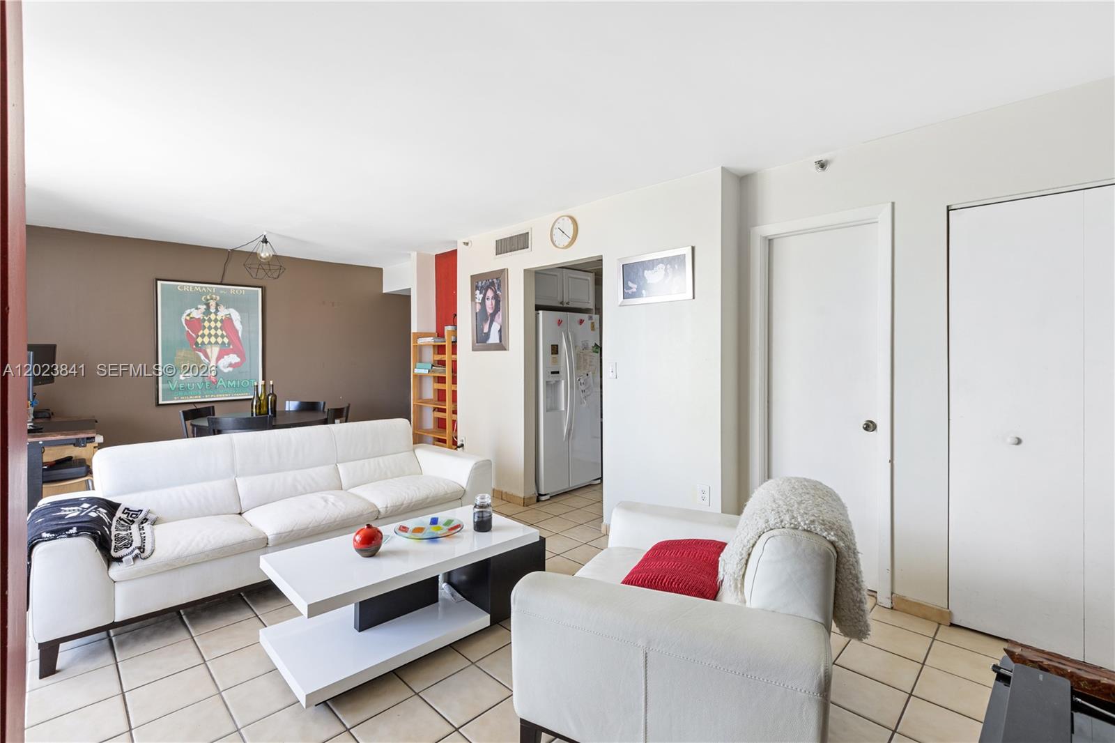 A living room features a white sofa, a matching armchair, and a coffee table on tile floors — 2457 Collins Ave # 1602, Miami Beach FL 33140, MIAMI BEACH, FL