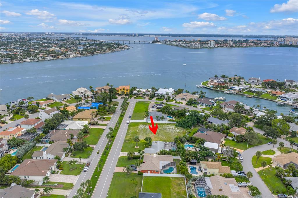 An aerial view shows a vacant residential lot marked by a red arrow near water — 255 MONTE CRISTO BOULEVARD, ST PETERSBURG, FL