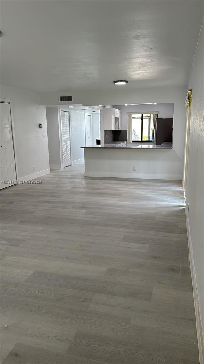 A living area with light wood-look flooring opens to a kitchen with a breakfast bar — 331 Lakeview Dr # 101, Weston FL 33326, WESTON, FL
