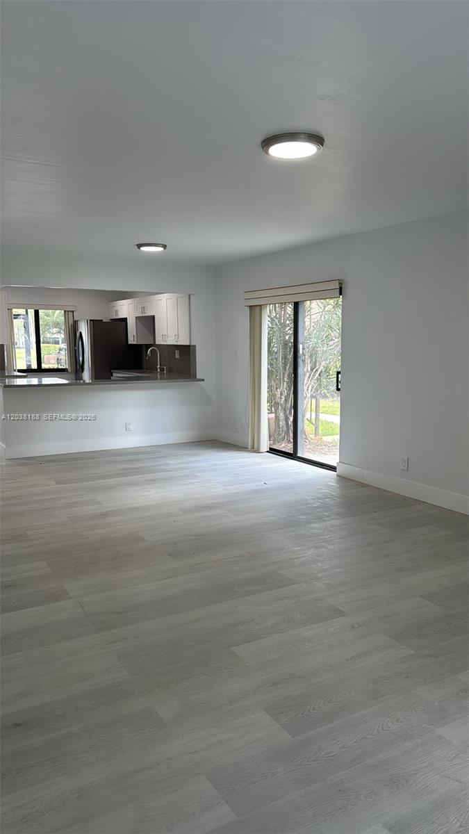 This living room features light-colored wood-look flooring, a kitchen pass-through, and a sliding glass door — 331 Lakeview Dr # 101, Weston FL 33326, WESTON, FL