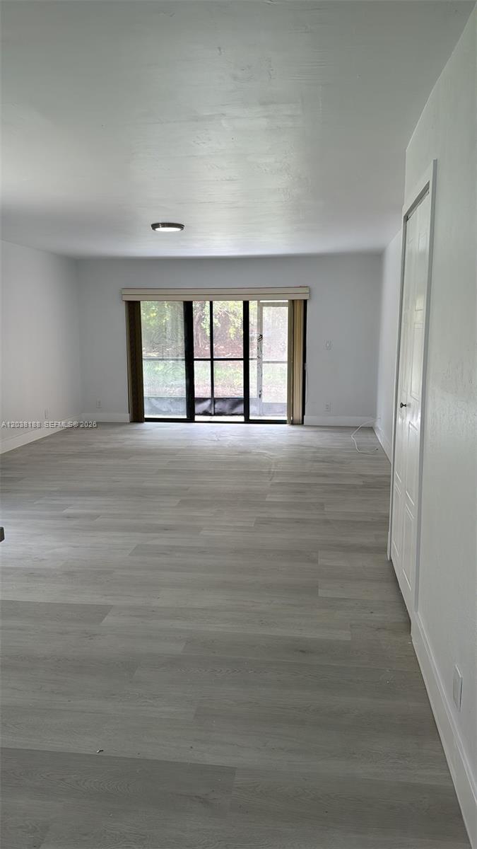 This living room features light gray wood-look flooring, white walls, and a sliding glass door — 331 Lakeview Dr # 101, Weston FL 33326, WESTON, FL