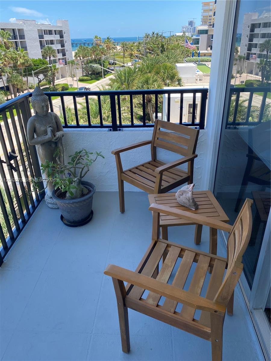 A balcony features two wooden chairs, a small table, a potted plant, and a Buddha statue — 531 N ocean # 611, Pompano Beach FL 33062, POMPANO BEACH, FL