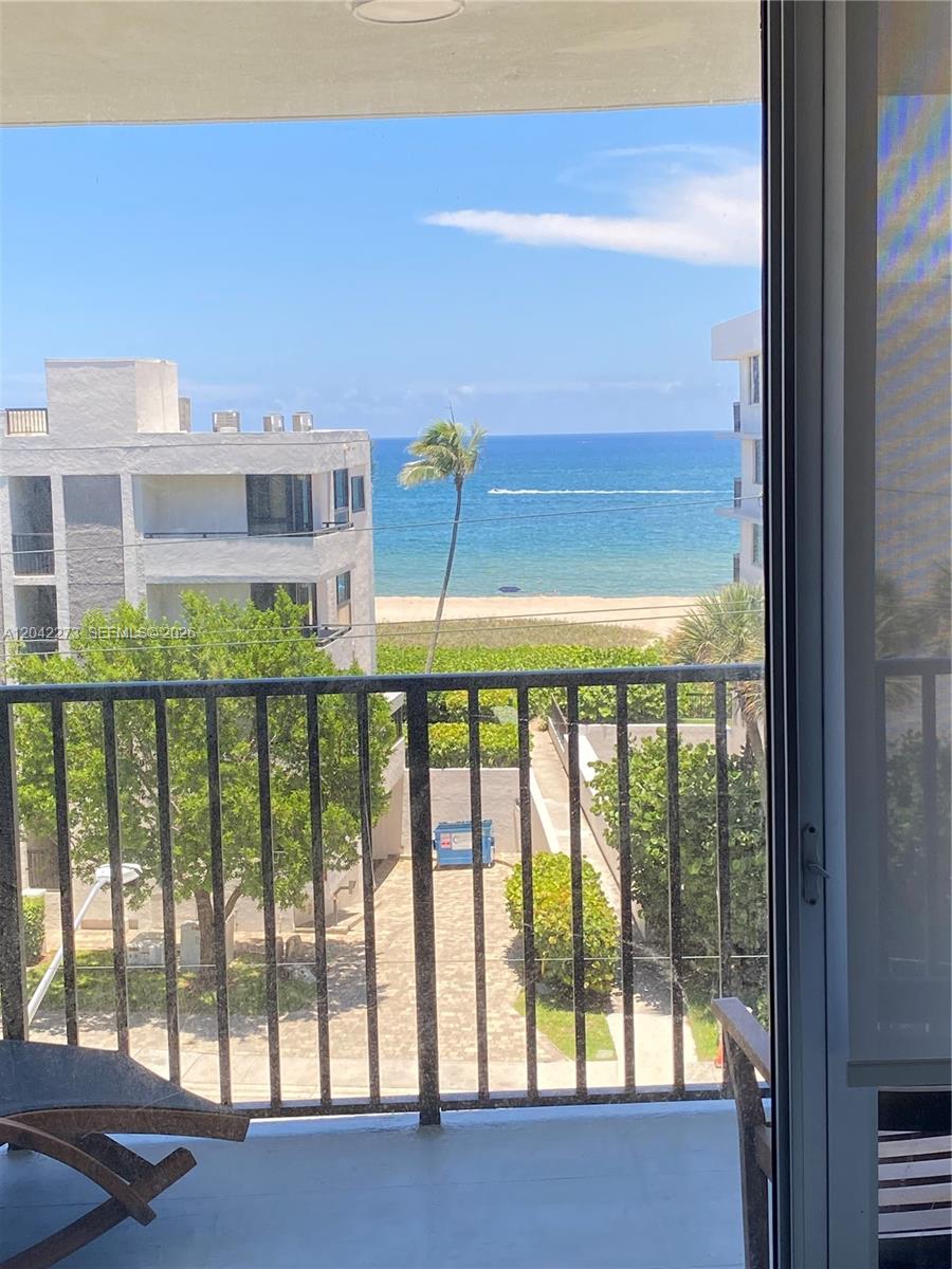 A balcony view overlooks a sandy beach, the ocean, and a neighboring building — 531 N ocean # 611, Pompano Beach FL 33062, POMPANO BEACH, FL