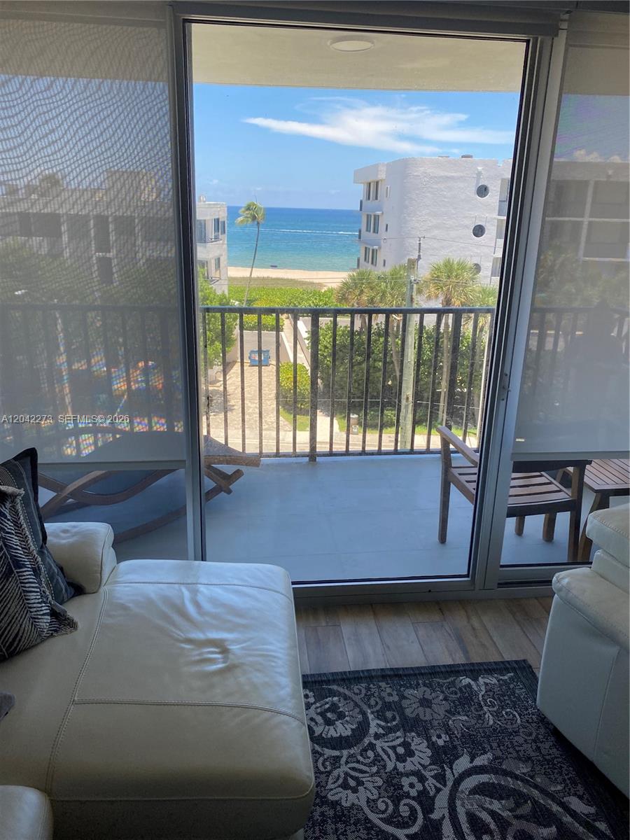 A living room with a white sofa overlooks a balcony with an ocean view — 531 N ocean # 611, Pompano Beach FL 33062, POMPANO BEACH, FL