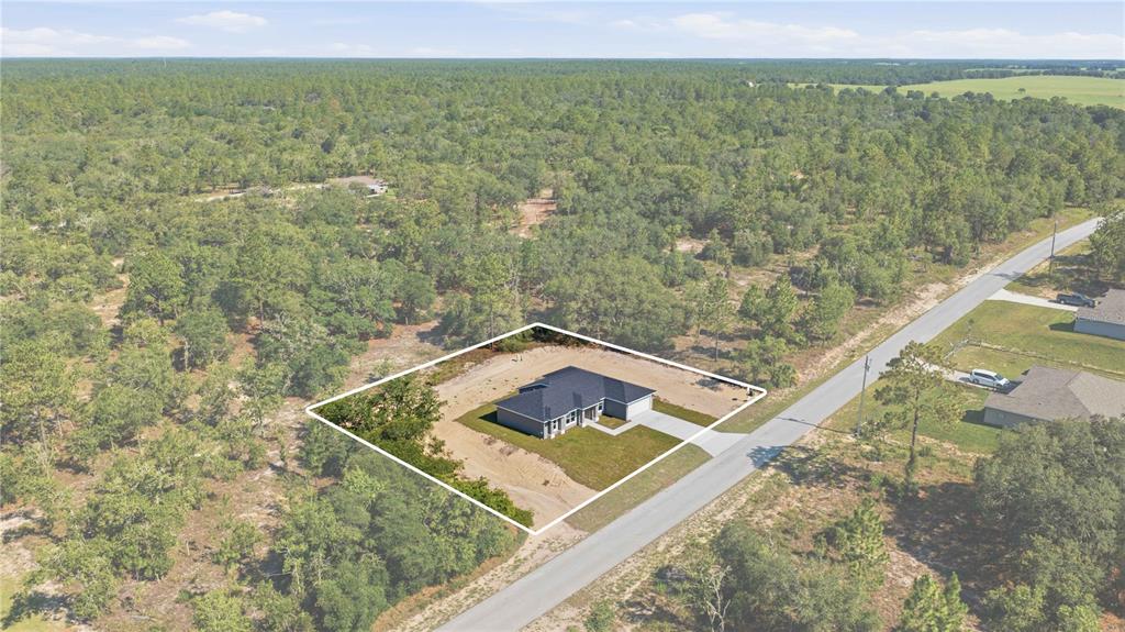 An aerial view shows a single-story house situated on a large, partially cleared wooded lot — 1690 SW VIBURNUM ROAD, DUNNELLON, FL