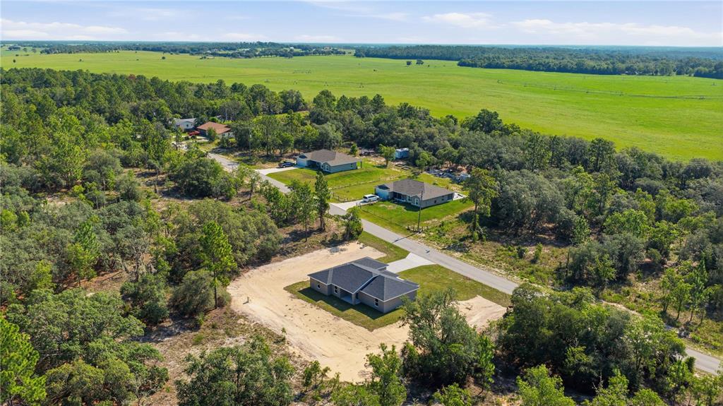 An aerial view shows a new house under construction surrounded by trees and open fields — 1690 SW VIBURNUM ROAD, DUNNELLON, FL