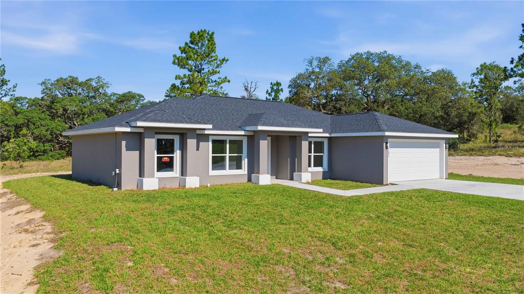 A single-story gray house with a white garage door and a grassy yard — 1690 SW VIBURNUM ROAD, DUNNELLON, FL