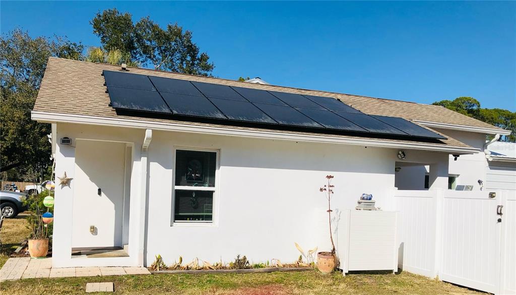 A white exterior wall of a house features a solar panel array on the roof — 405 CONNECTICUT AVENUE, FLAGLER BEACH, FL