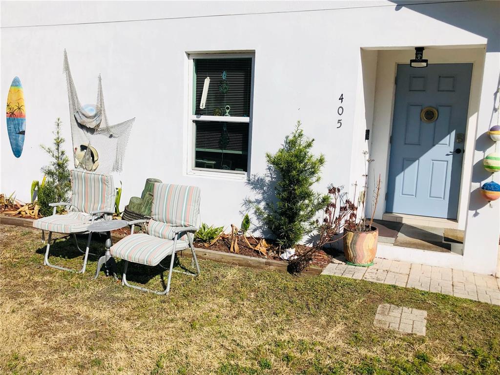 The exterior of a white house features a blue front door, two chairs, and decor — 405 CONNECTICUT AVENUE, FLAGLER BEACH, FL