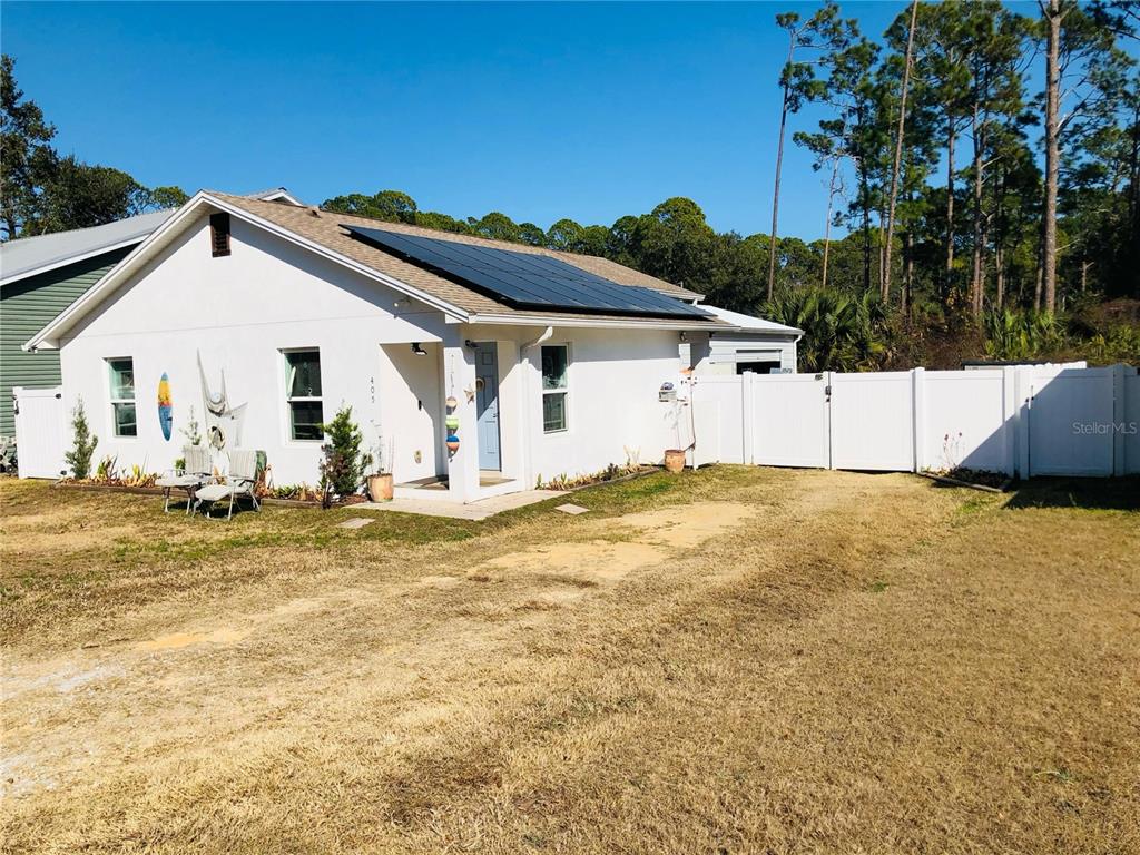 A white single-story house with solar panels on the roof and a white vinyl fence — 405 CONNECTICUT AVENUE, FLAGLER BEACH, FL