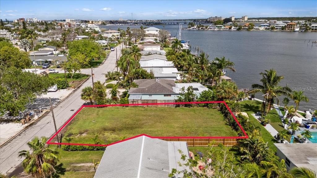 An aerial view shows a vacant, rectangular waterfront lot outlined in red — 14033 E PARSLEY DRIVE, MADEIRA BEACH, FL